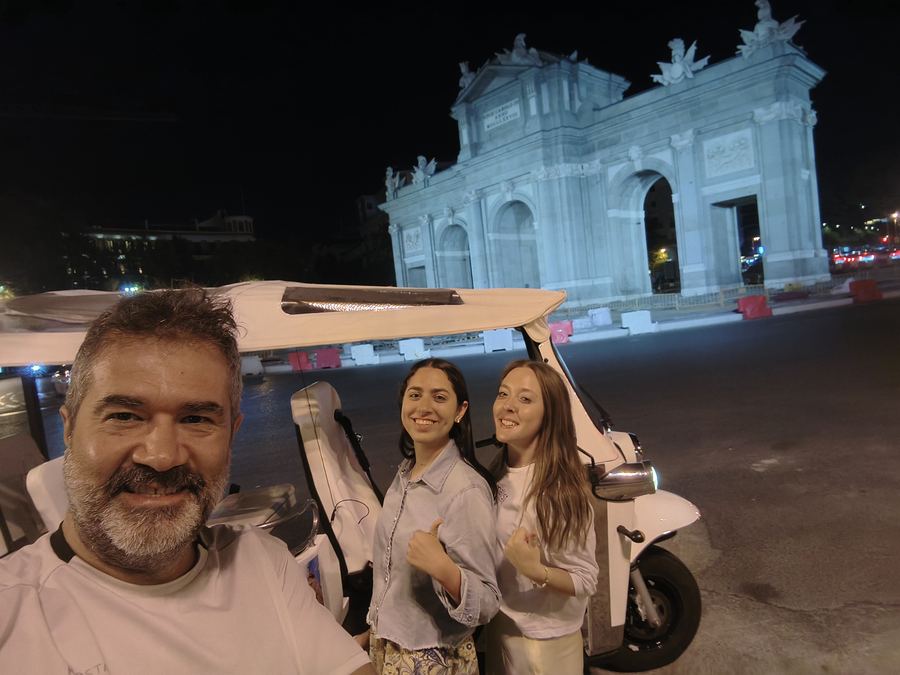 Night Tuk Tuk tour in front of the illuminated Puerta de Alcalá, Madrid